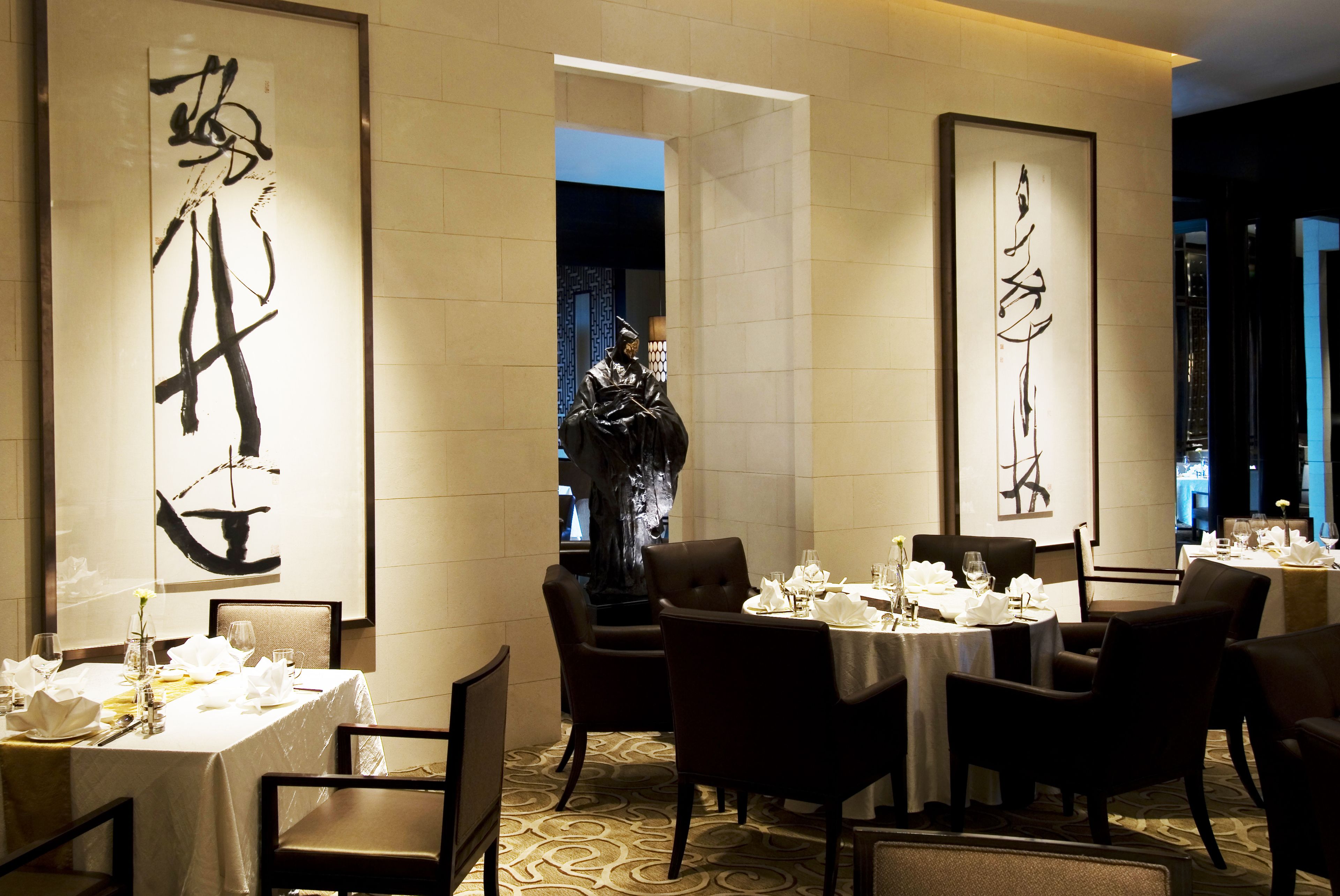 Un ristorante con tavoli apparecchiati per la cena, con opere di calligrafia alle pareti.