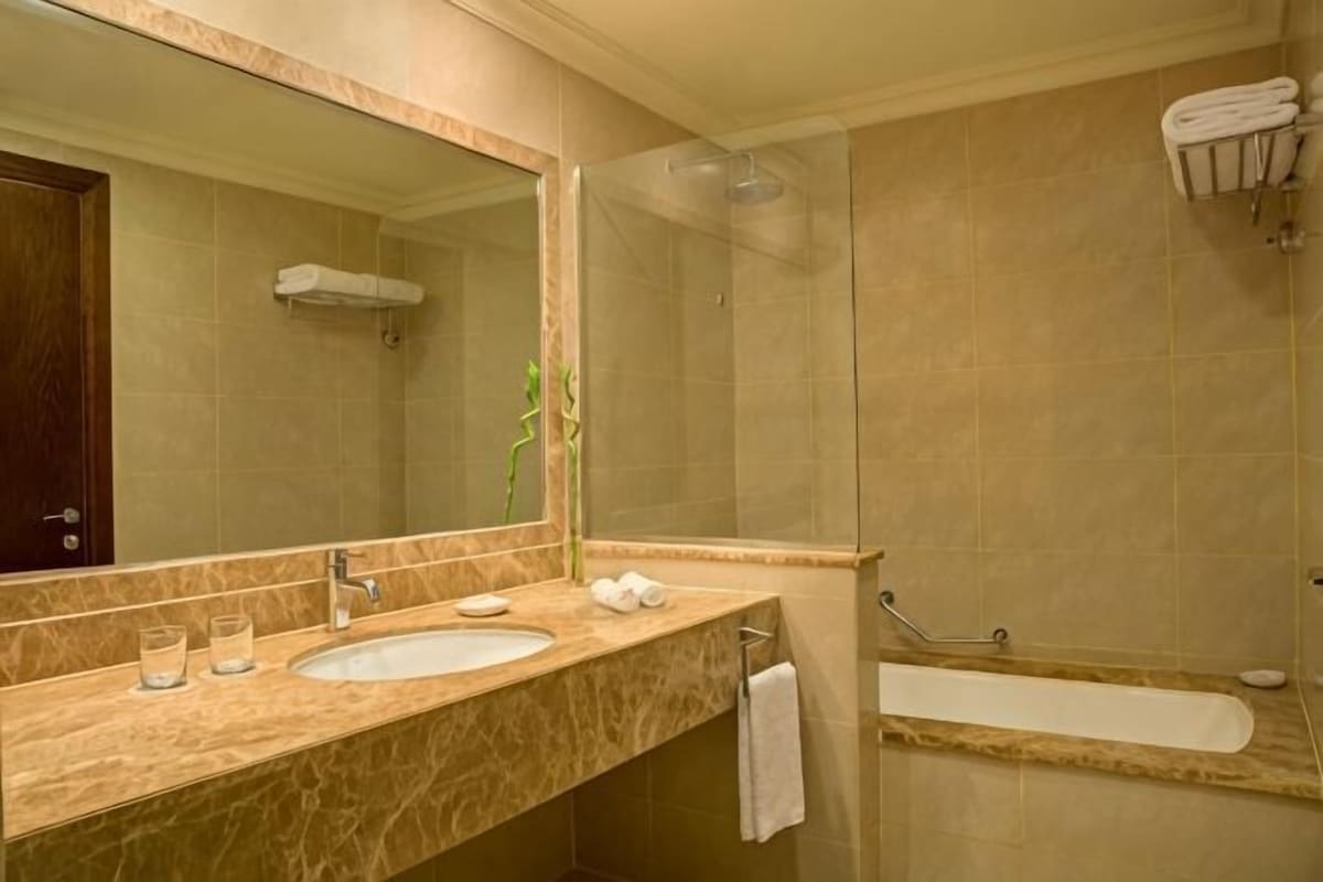 A bathroom with a marble sink, a large mirror, a shower, and a bathtub.