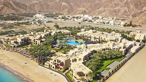 Un resort con piscina central, varias edificaciones y una playa.