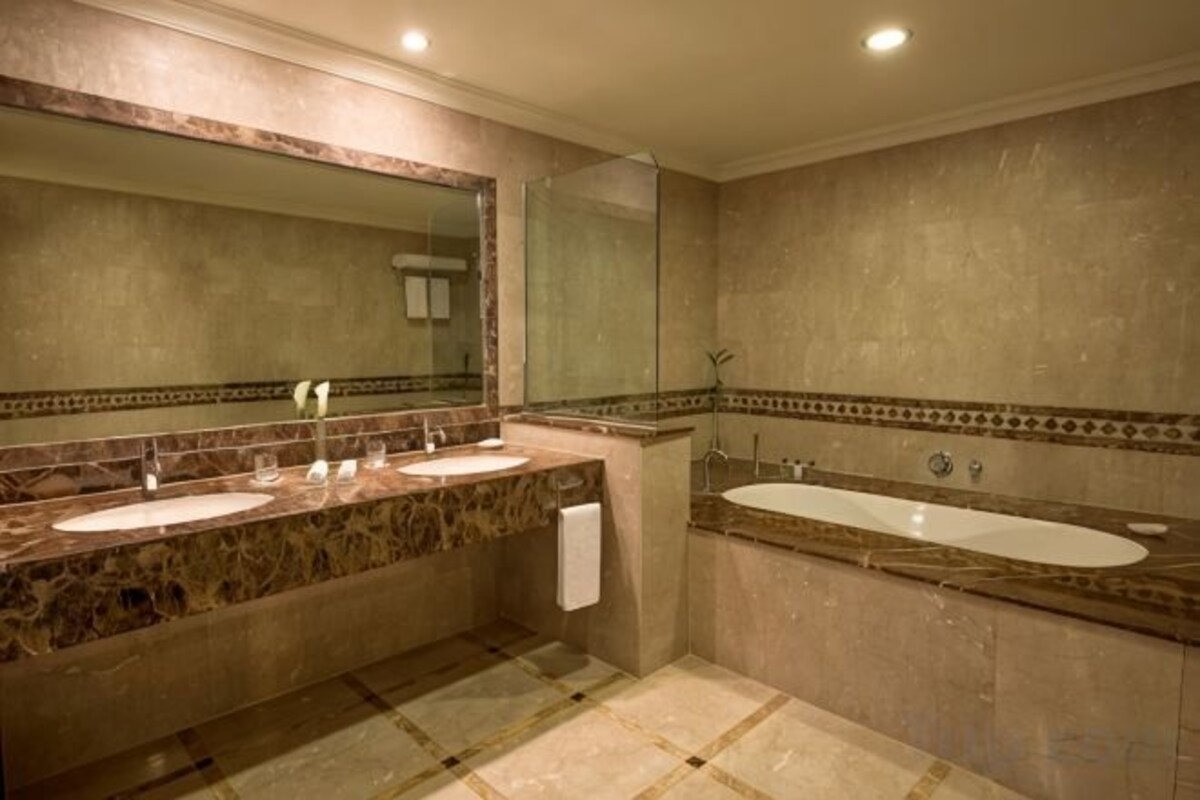 Un baño con dos lavamanos, una bañera y un espejo grande.