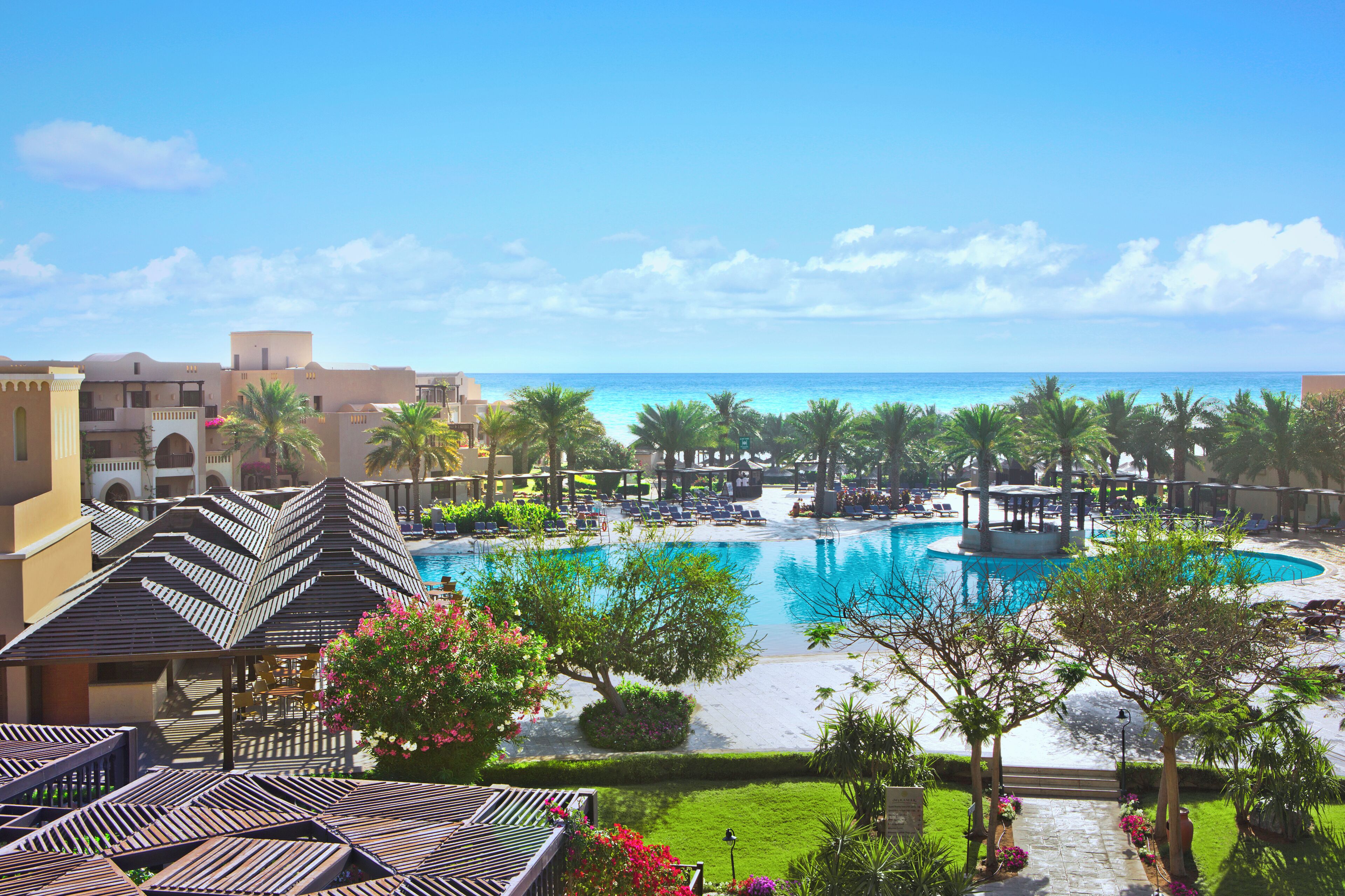 Un resort con piscina, palmeras y vista al océano.