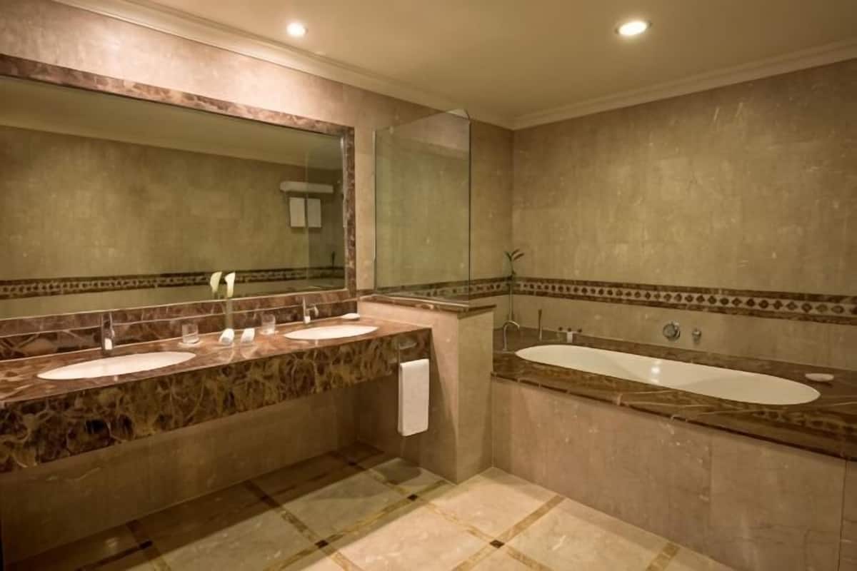A bathroom with two sinks, a bathtub, and a large mirror.