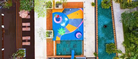 Vista aérea de un hotel con piscina, un mural colorido y mobiliario exterior.