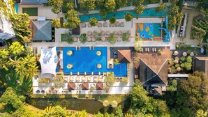 Vista aèria d'un complex turístic amb diverses piscines, zones d'estar a l'aire lliure i una vegetació exuberant.