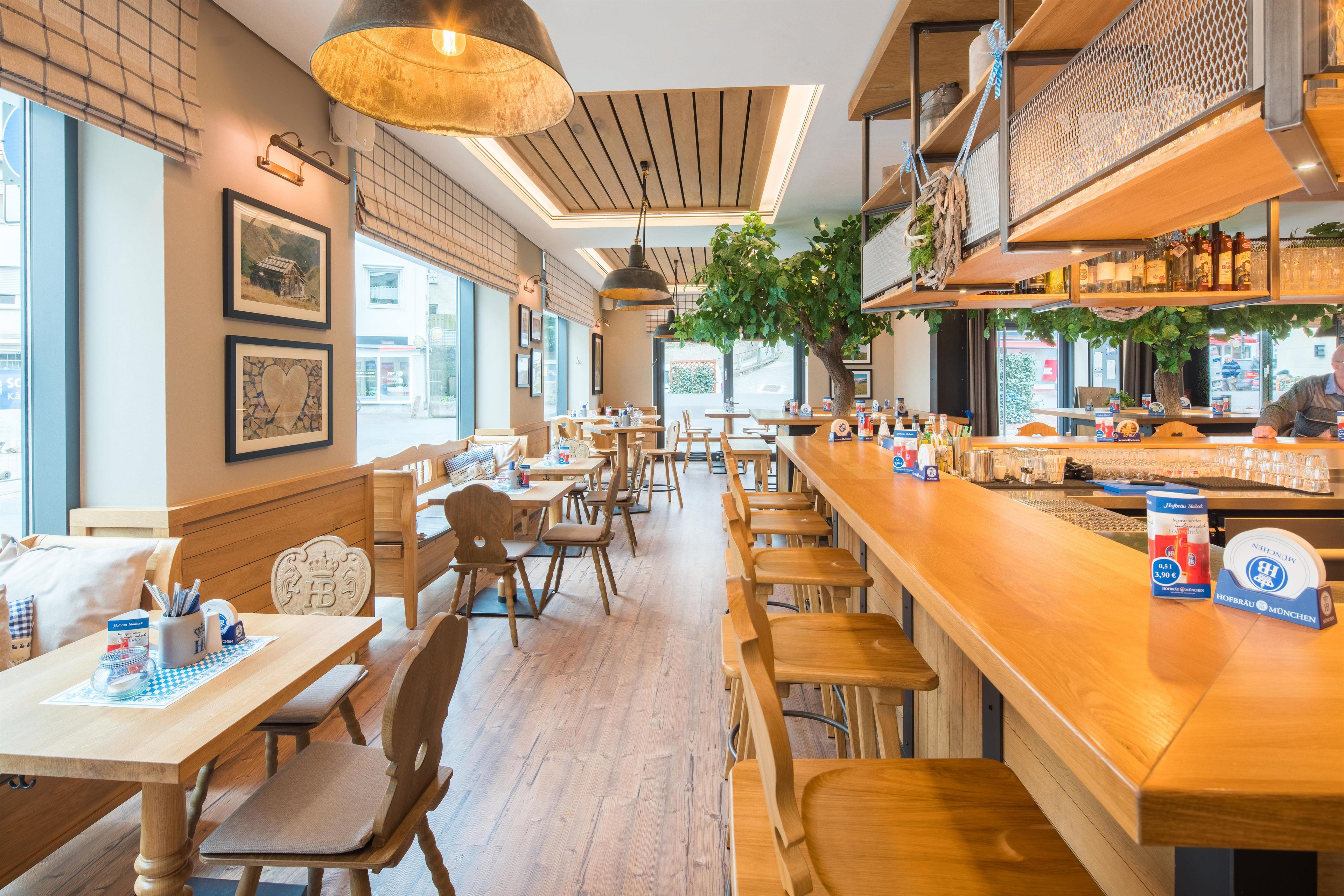 A restaurant interior with wooden furniture, a bar area, and a view of the street outside.