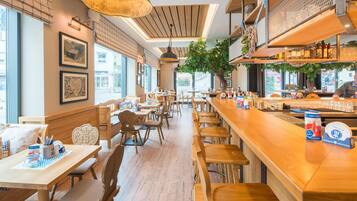 A restaurant interior with wooden furniture, a bar area, and a view of the street outside.