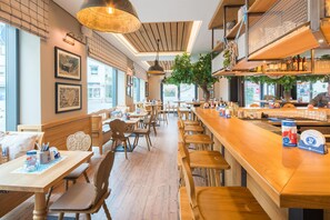 L’intérieur d’un restaurant, avec des meubles en bois, un coin bar et une vue sur la rue.
