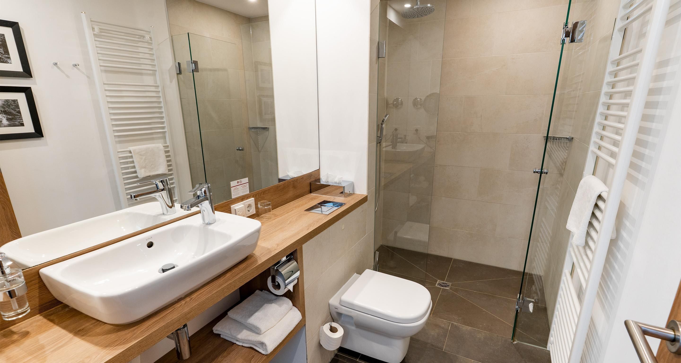 A modern bathroom with a large sink, toilet, and glass-enclosed shower.
