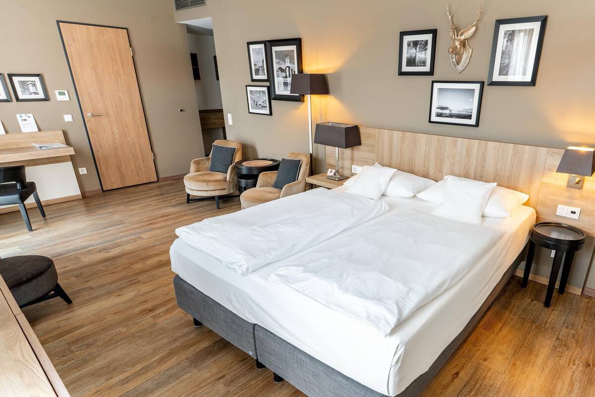 Une chambre d’hôtel avec un grand lit, un bureau, deux chaises et une table ronde.