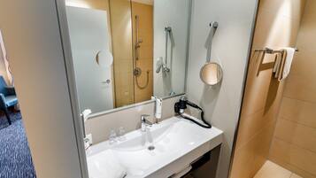 Un baño moderno con un lavamanos blanco, una ducha de mano, un perchero para toallas y un espejo.