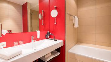 Un baño con un lavamanos blanco, un espejo, una pared de acento roja, una ducha y una bañera.