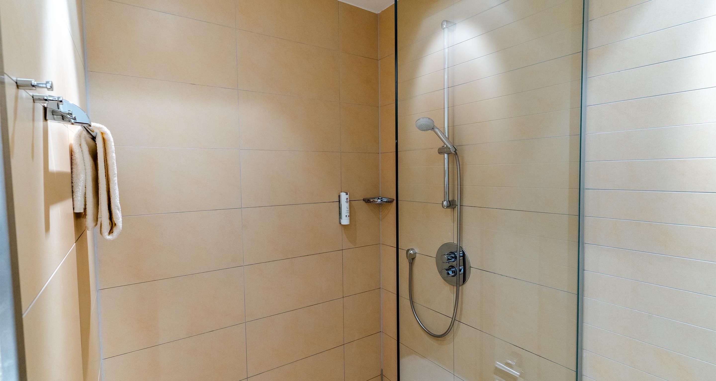 Una ducha con cabezal de ducha manual y panel de control en la pared.