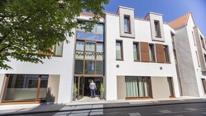 Un bâtiment moderne doté de grandes fenêtres, d’un toit plat et d’une personne se tenant à l’entrée.