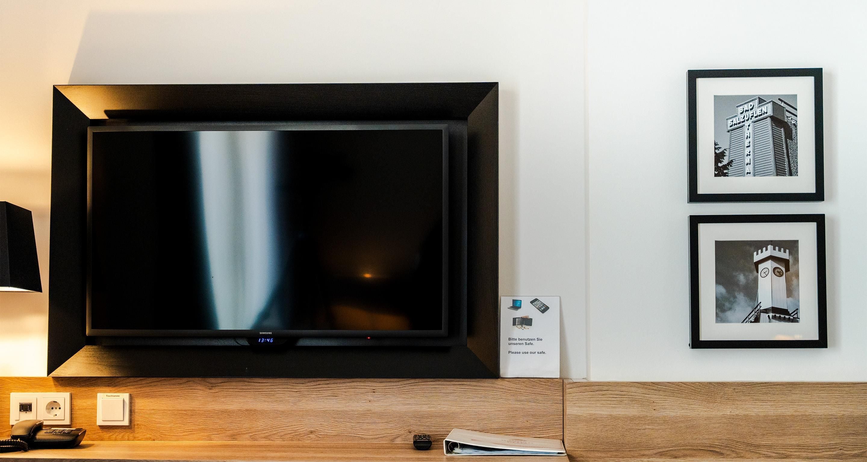 Un televisor montado en la pared con un cuadro enmarcado debajo.