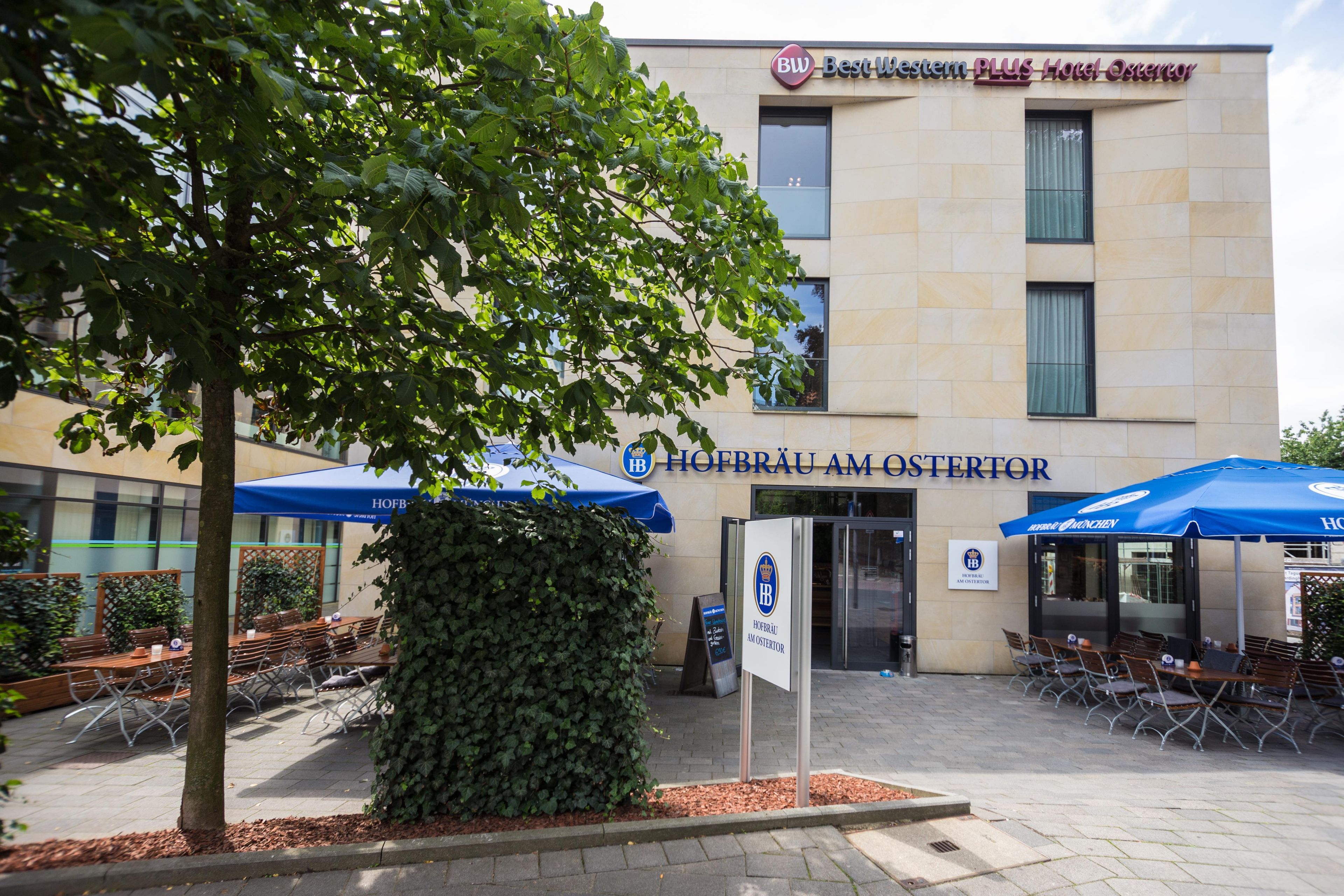 A hotel entrance with outdoor seating and a sign for Hofbrau Am Osterreich.