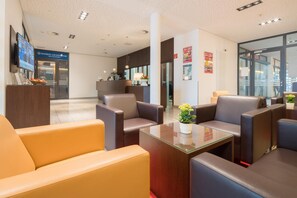 A hotel lobby with leather seating, a reception desk, and a large window.