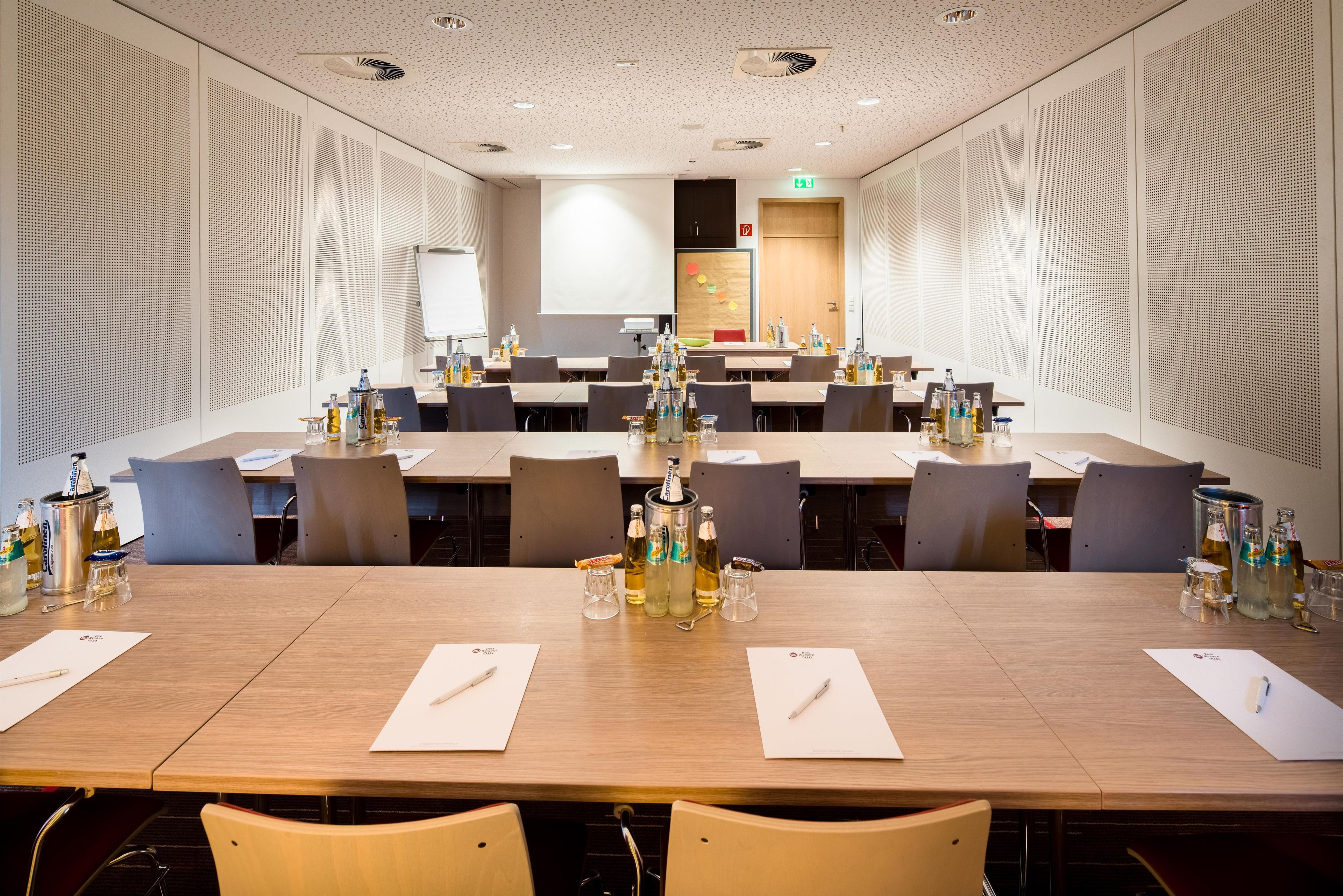 A conference room with multiple tables, chairs, and various beverages.