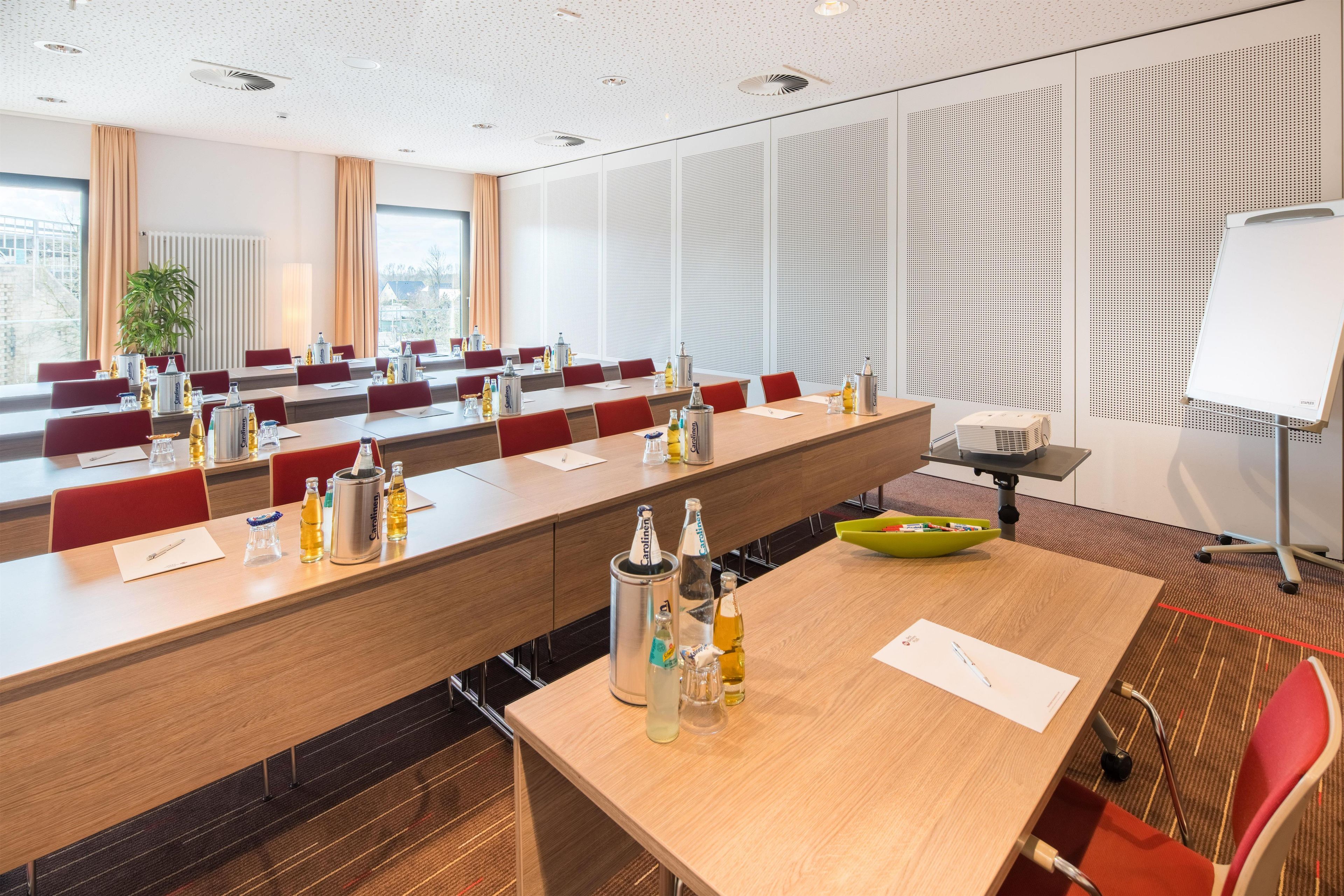 Une salle de conférence équipée de plusieurs tables, de chaises et d’un tableau blanc.