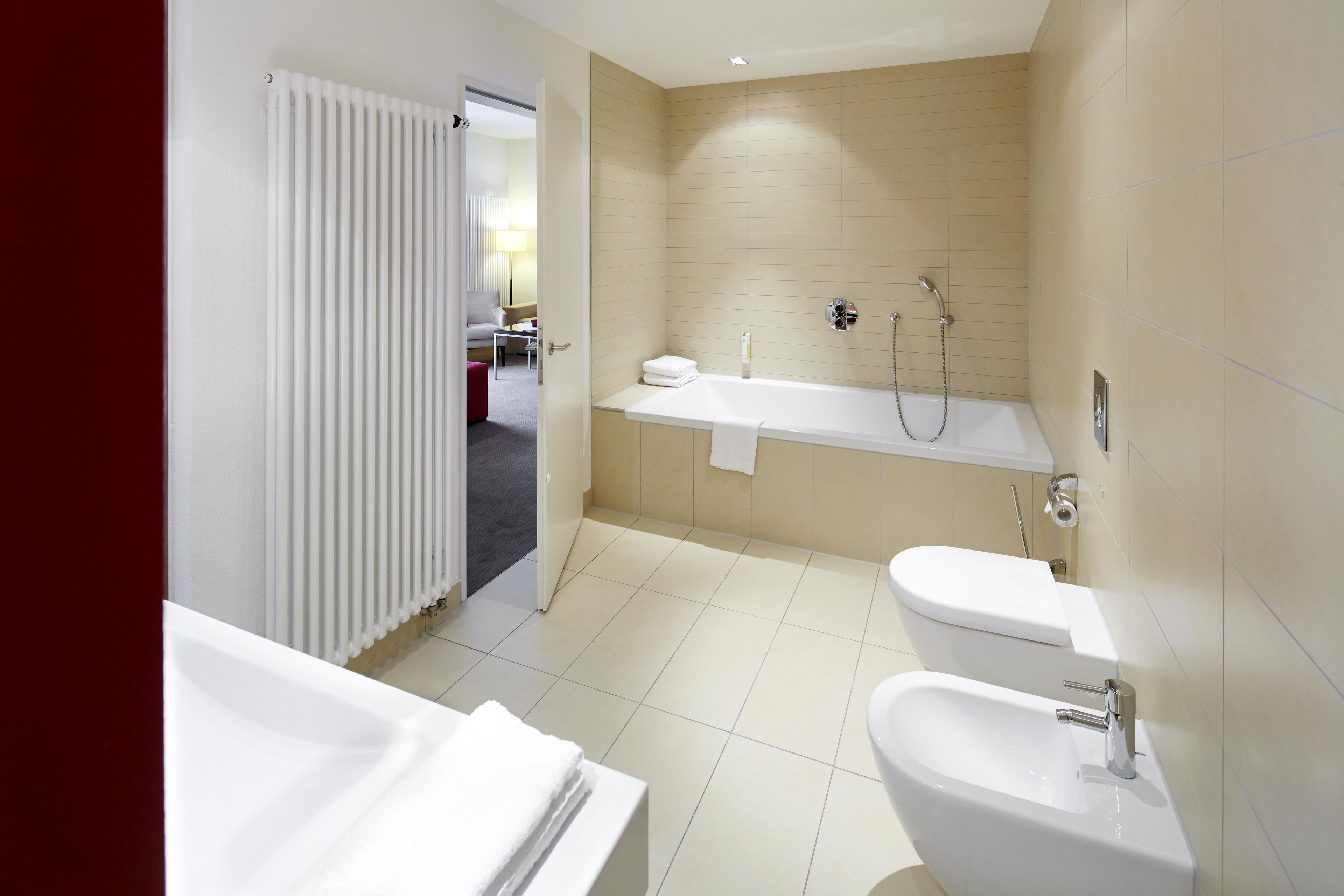 A modern bathroom with a bathtub, toilet, and bidet.