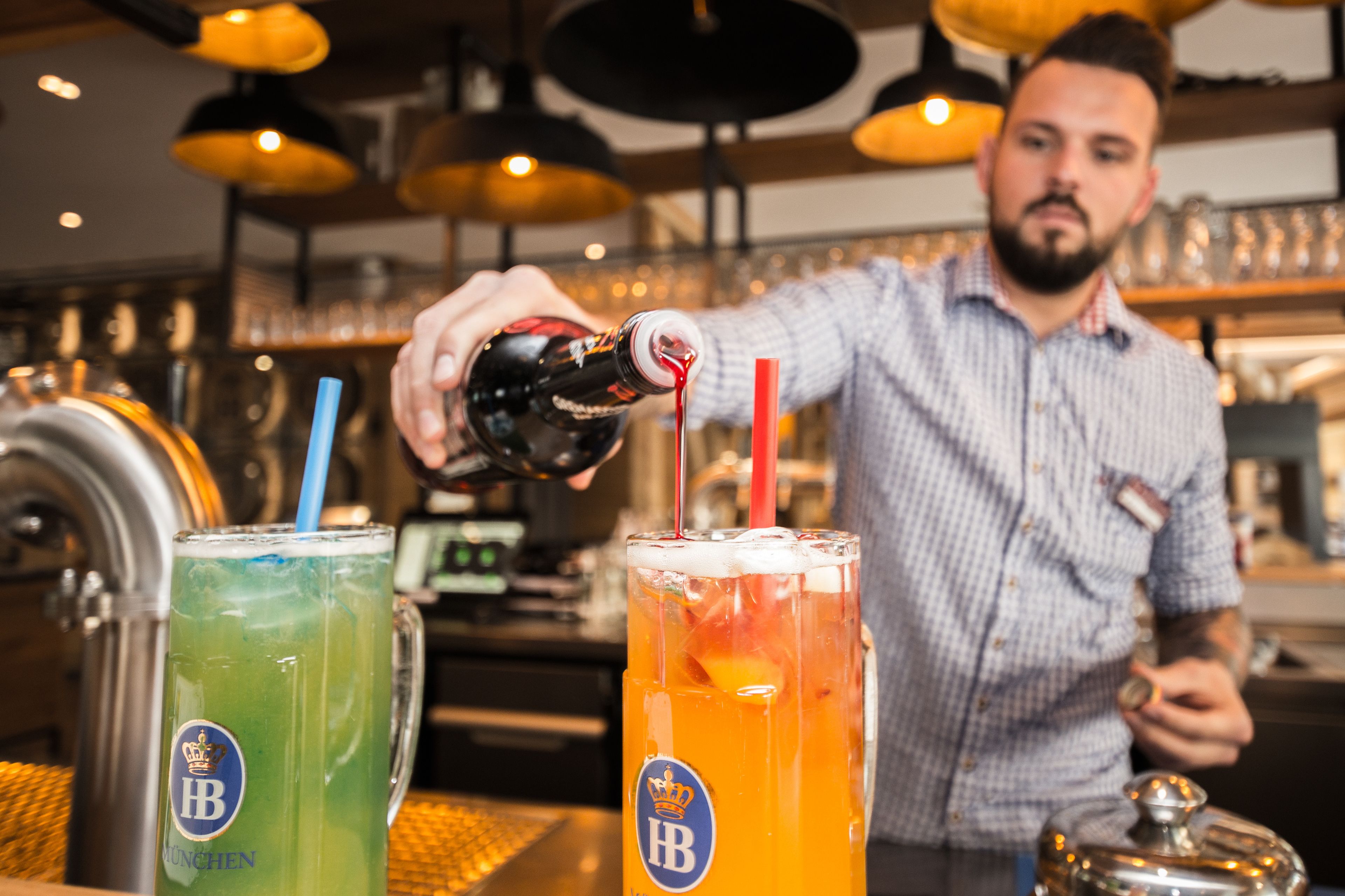 Ein Barkeeper gießt ein Getränk in ein Glas mit Trinkhalm.