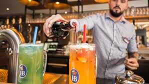 Ein Barkeeper gießt ein Getränk in ein Glas mit Trinkhalm.