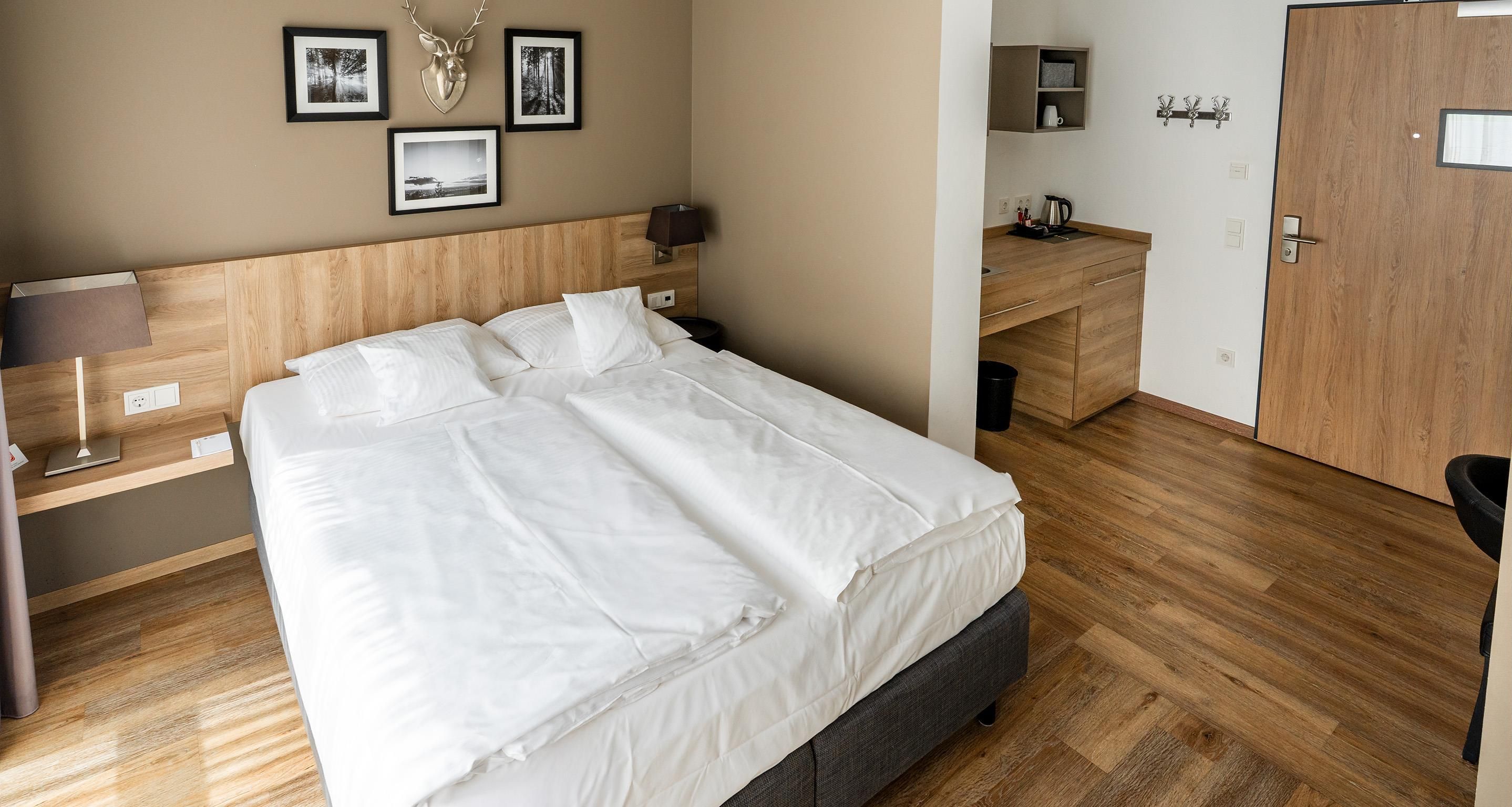 A hotel room with a large bed, a desk, and a wardrobe.