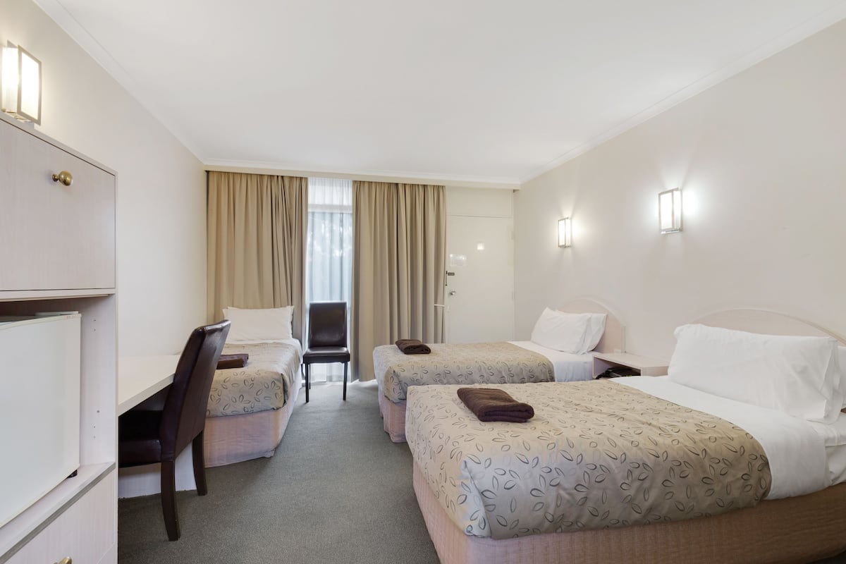 A hotel room with two beds, a desk, and a chair.
