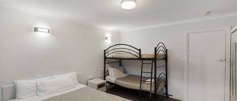 Habitación individual con literas, una mesita de noche y una puerta.