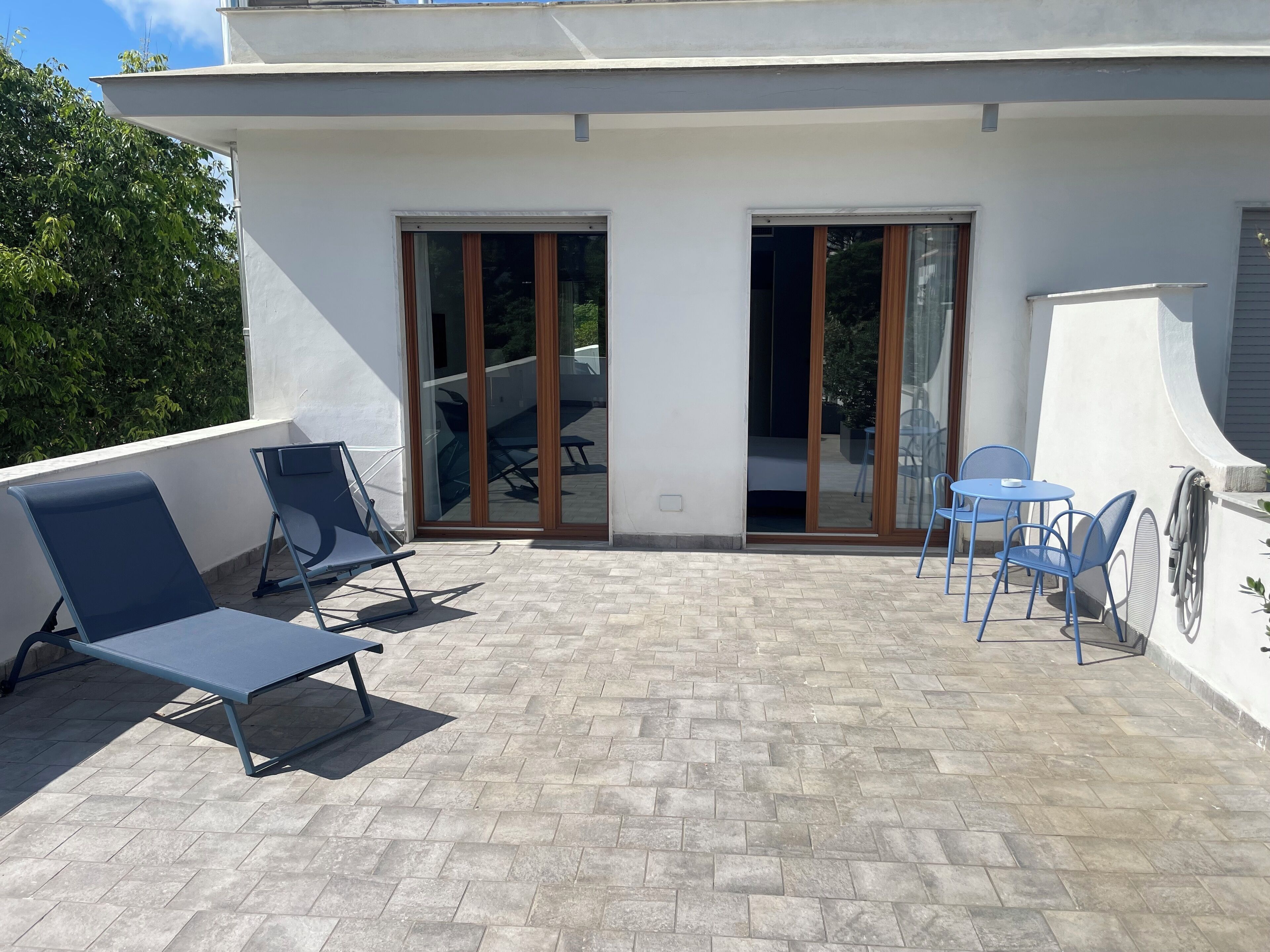 A rooftop patio with two lounge chairs, a small table, and a blue chair.