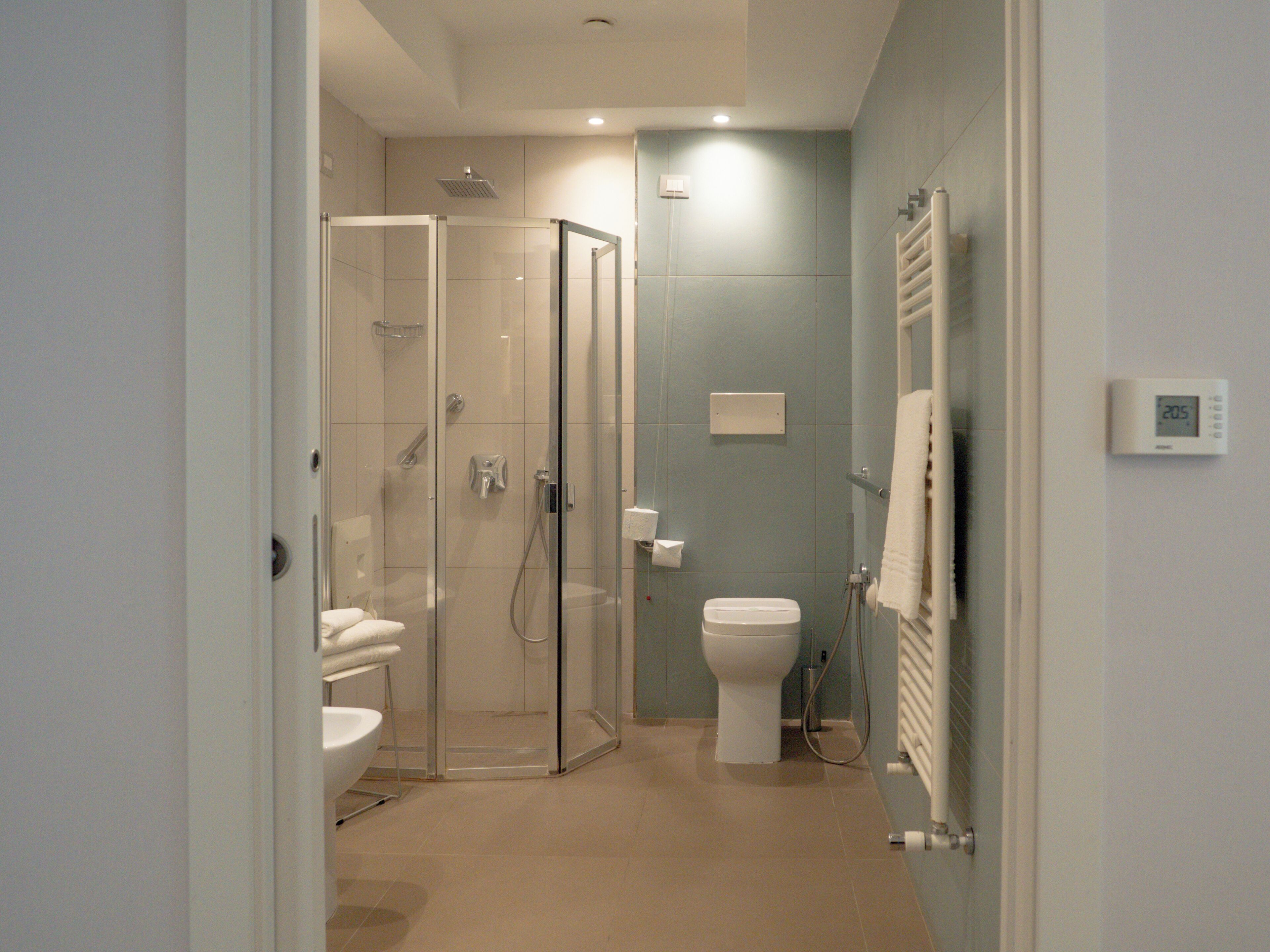 A modern bathroom with a glass shower enclosure, a toilet, and a sink.