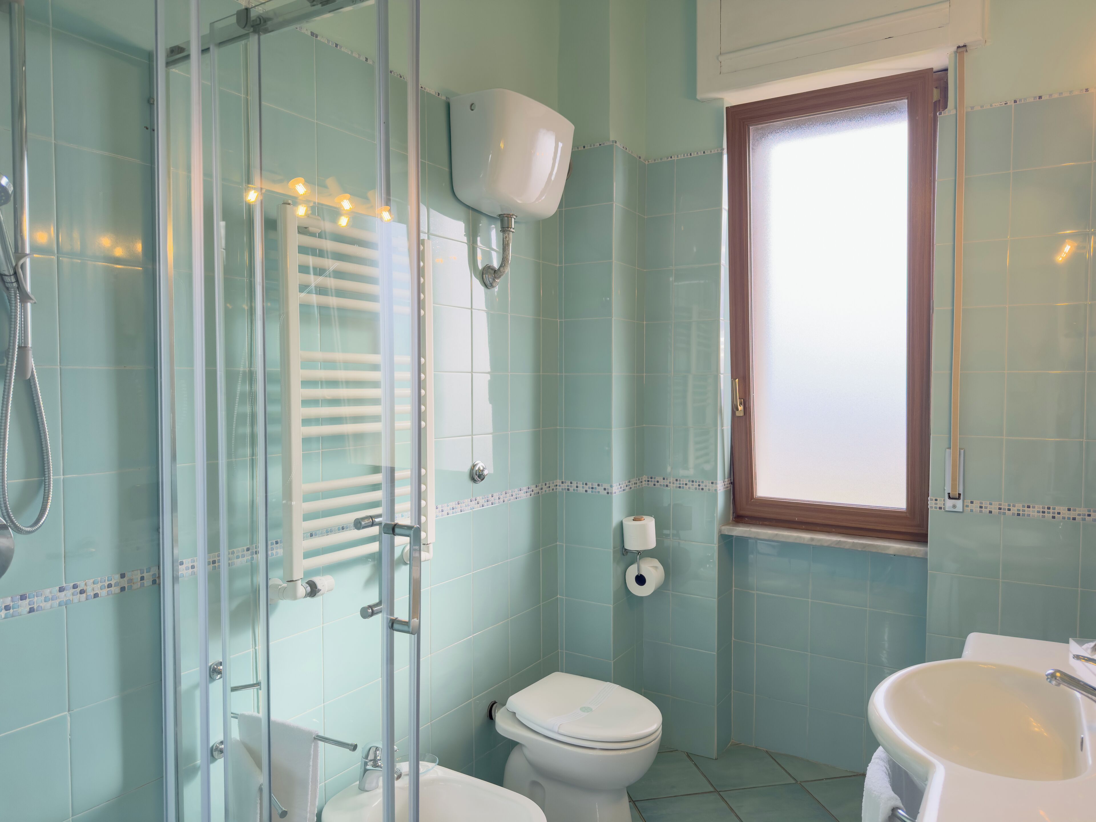 Un bagno con box doccia in vetro, un water e un lavandino.