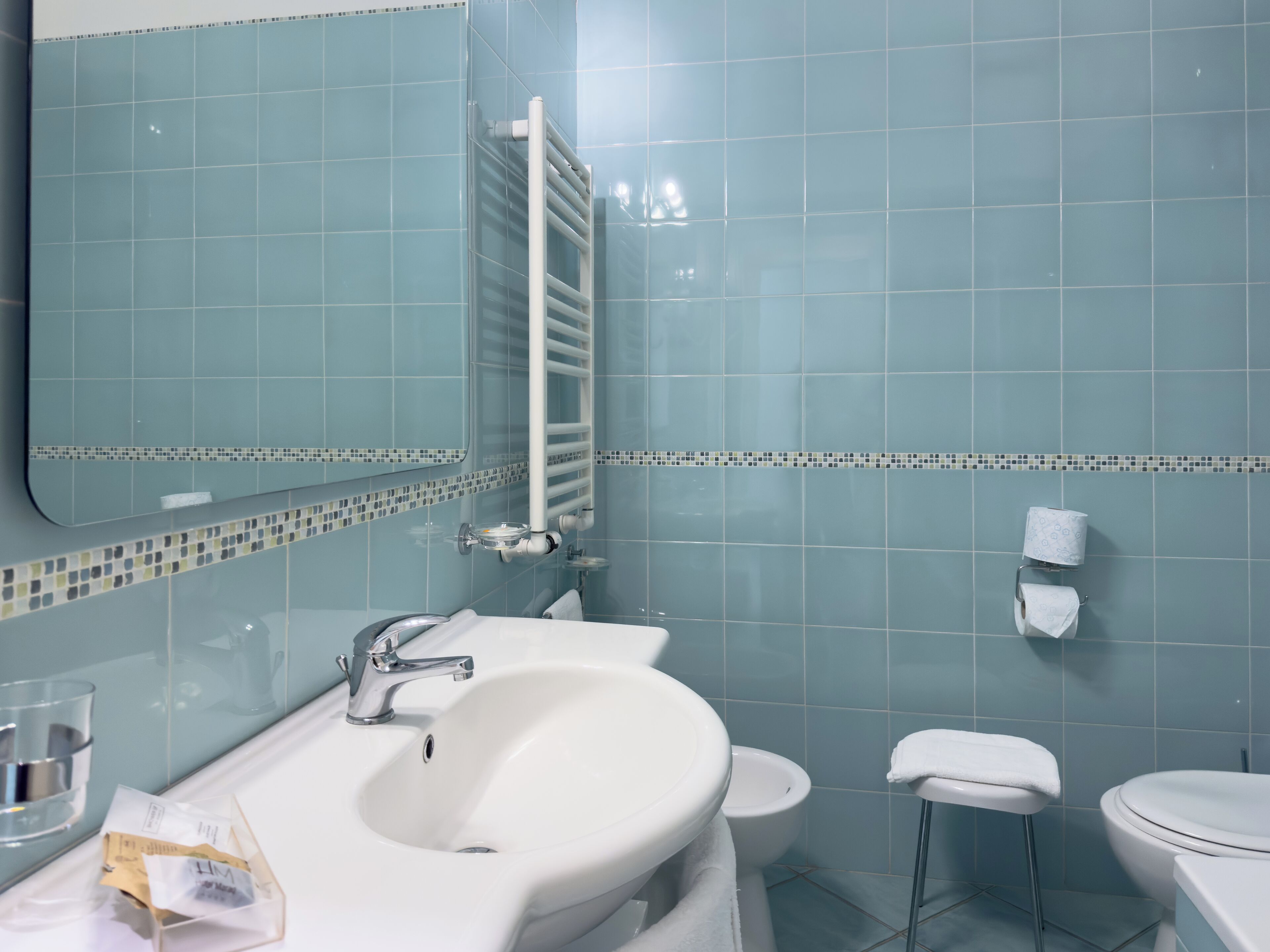 A bathroom with a sink, mirror, toilet, and towel rack.