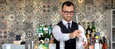 Un cantinero detrás de una barra con diversas botellas de licor y vasos.