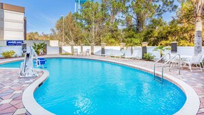 A swimming pool with a water tower in the background, surrounded by trees and a building with a 'mobile mini' sign. - La Quinta Inn & Suites by Wyndham St. Augustine (St. Augustine)