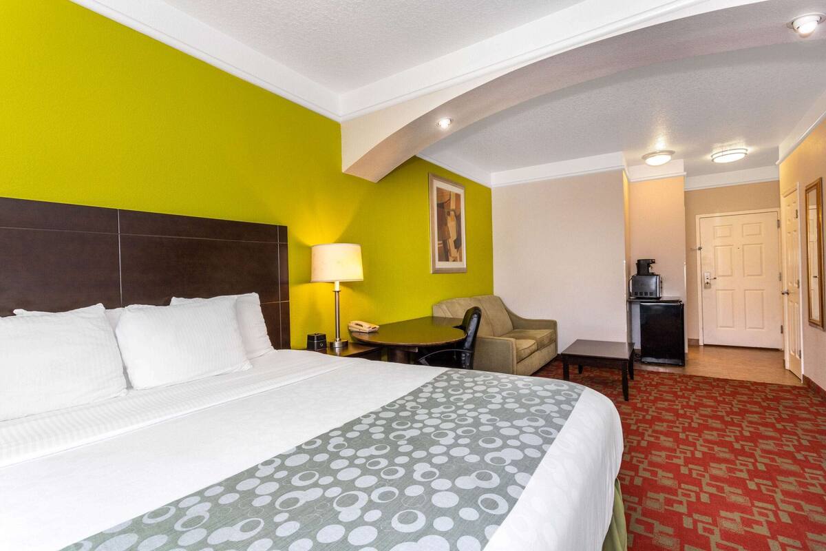 Une chambre d’hôtel avec un grand lit, un bureau, une chaise et une petite kitchenette.