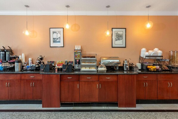 A breakfast bar with coffee makers, a fruit basket, and a coffee station.
