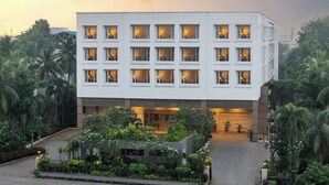 Un hotel moderno con fachada blanca, múltiples ventanales y un jardín ajardinado.