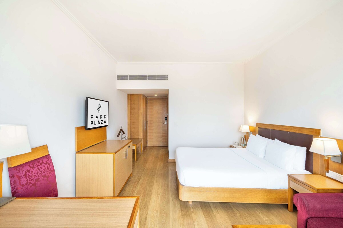 Una habitación de hotel con cama, mesitas de noche, escritorio, silla y armario.