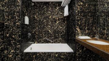 A modern bathroom with a black marble sink, a standalone bathtub, and a towel rack.