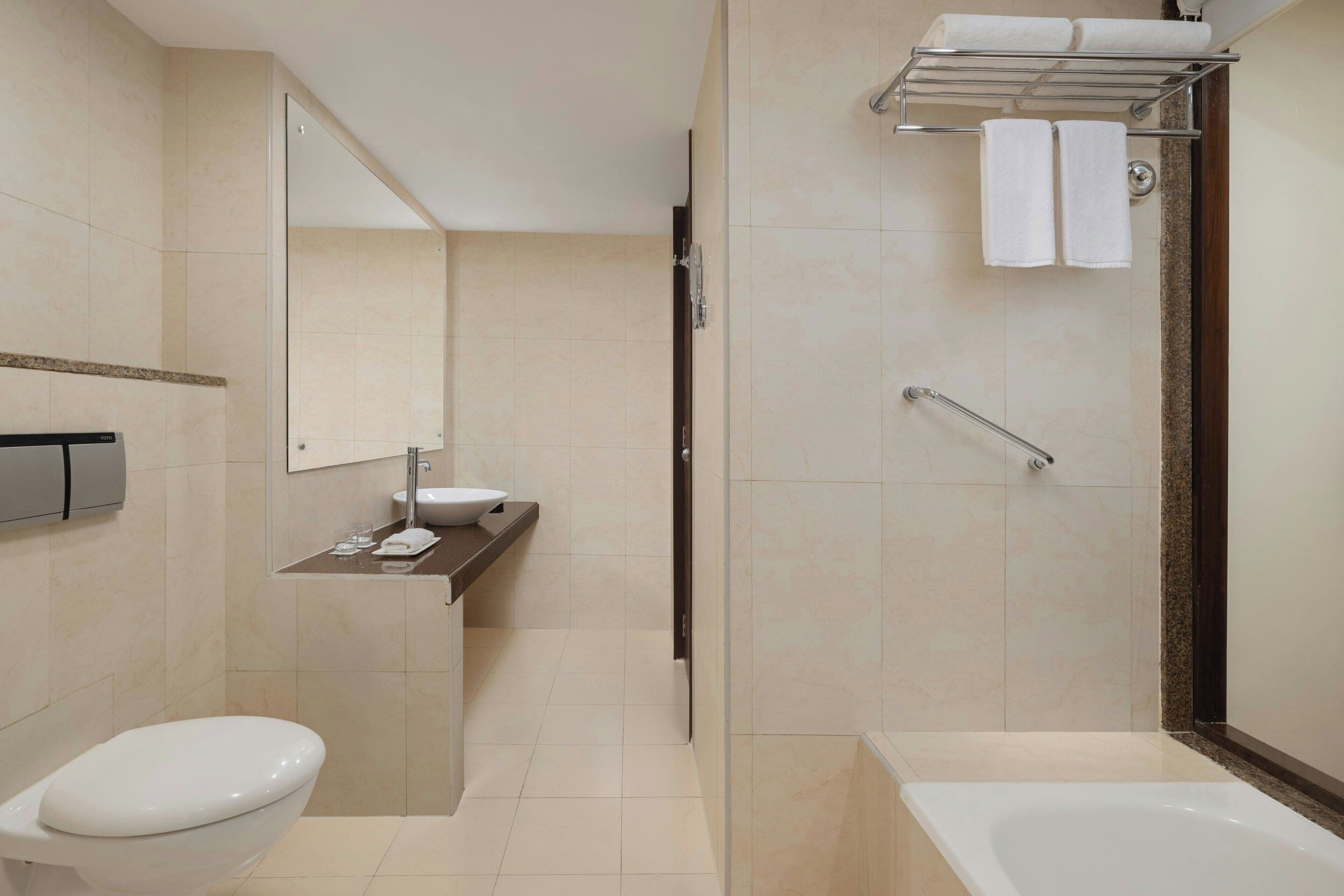 A modern bathroom with a toilet, sink, and bathtub.