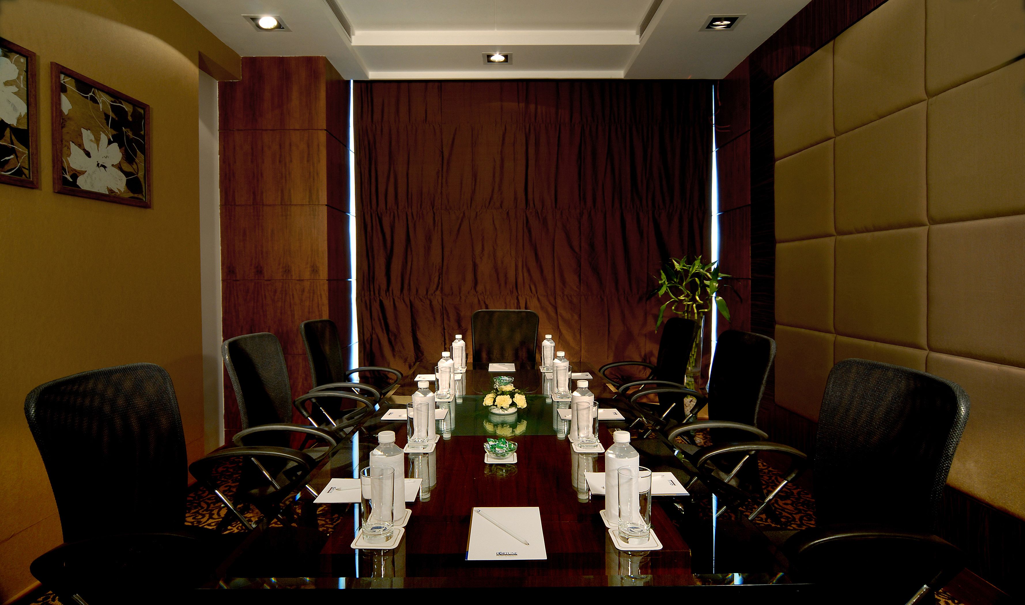 A conference room with a long table, chairs, water bottles, and a vase with flowers.