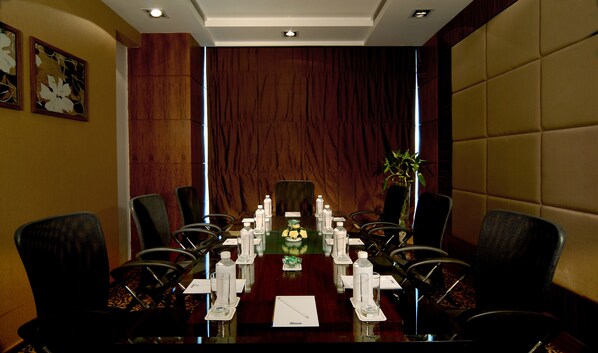 A conference room with a long table, chairs, water bottles, and a vase with flowers.