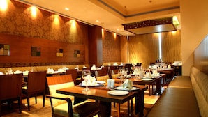 Un restaurante con mesas y sillas de madera, un banco largo y una pared con un diseño.