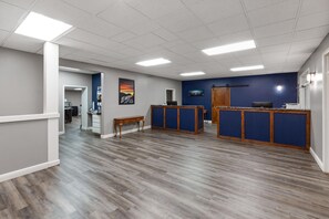 A spacious room with a wooden floor, a reception desk, and a door leading to another area. - Angel Inn Near IMAX, a Travelodge by Wyndham (Branson)