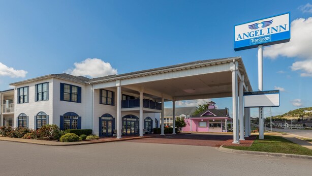A two-story building with a covered entrance and a sign for Angel Inn Travelodge.