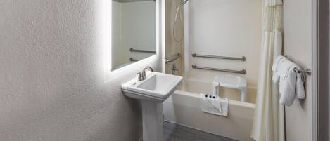 A bathroom with a pedestal sink, a bathtub, a shower, and a mirror.
