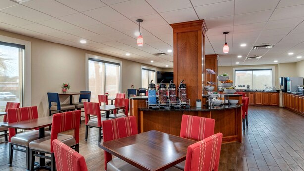 Um restaurante com assentos estofados em vermelho, um balcão central e cozinha ao fundo.
