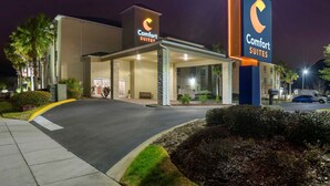 Um hotel Comfort Suites com entrada bem iluminada, área externa coberta e estacionamento.