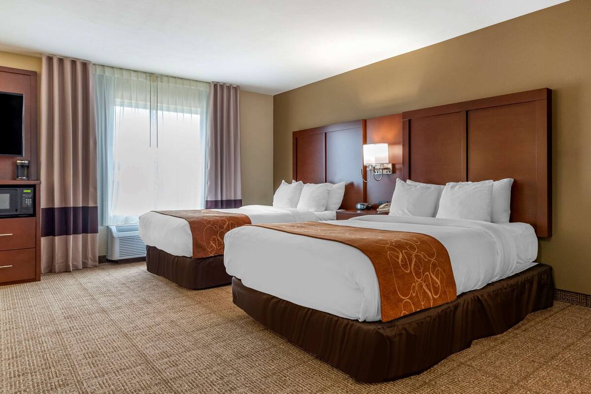 Habitación de hotel con dos camas, televisión, cafetera y ventana con cortinas.
