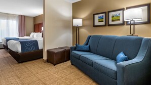Quarto de hotel com uma cama, duas mesas de cabeceira, um sofá e uma luminária na parede.